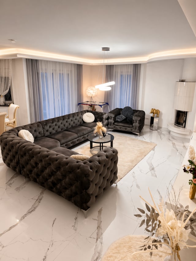 Lounge mit Kamin und bodentiefen Vorhängen in der Designer-Wohnung