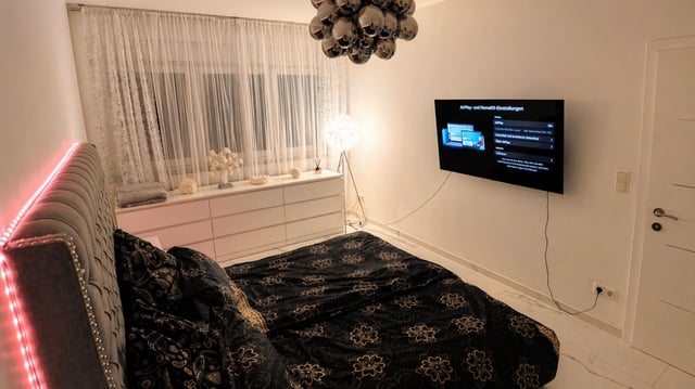 Schlafzimmer mit TV, Kommode und gepolstertem Kopfteil