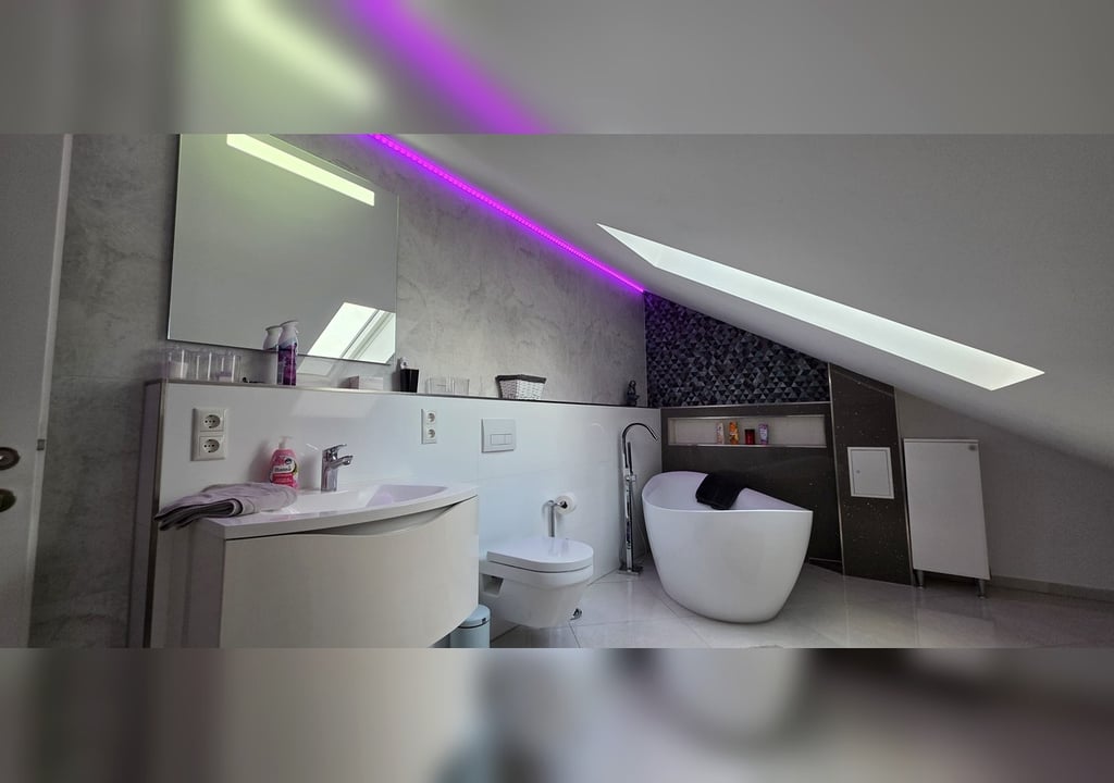 Freistehende Spa-Badewanne im Dachgeschoss mit Dachfenster und Ambient-Licht
