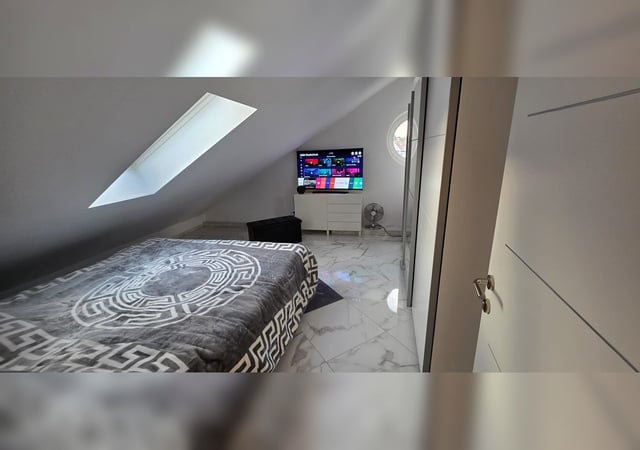 Schlafzimmer mit Doppelbett, Smart-TV und Dachfenster